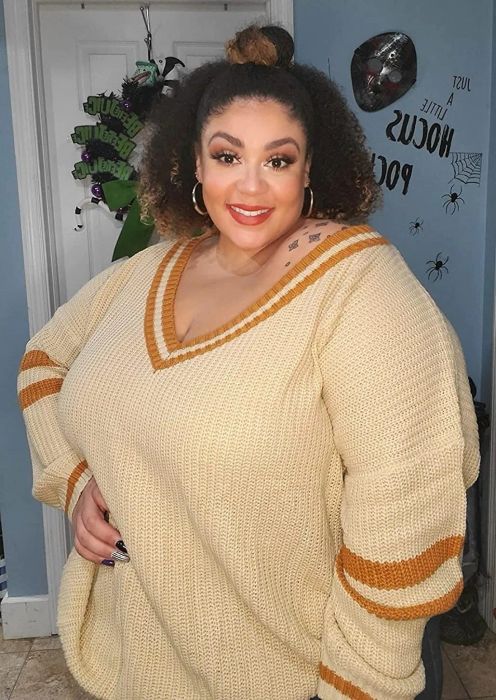 A reviewer showcasing the pullover featuring a striped V-neck and sleeves