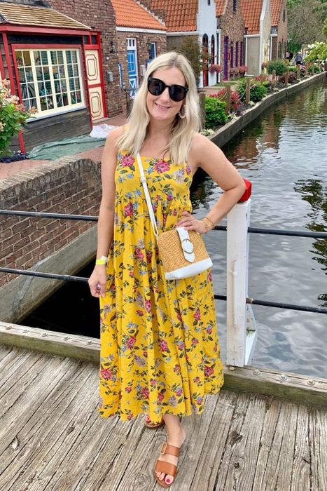 a reviewer wearing the flowy yellow dress adorned with a floral pattern