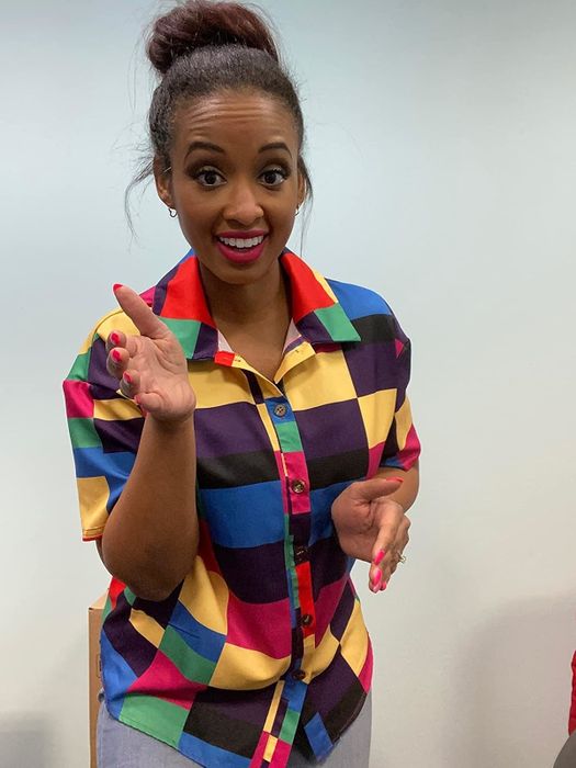A smiling person wearing a bright patterned shirt, gesturing with one hand. Perfect for a lively fashion feature