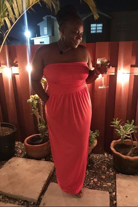 a reviewer wearing a pink strapless maxi dress, casually placing a hand in one of the side slit pockets