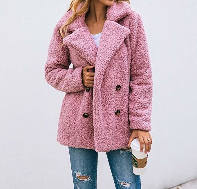 A model showcasing a pink teddy faux fur pea coat adorned with black buttons