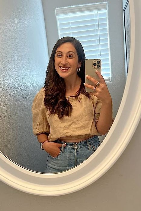 A reviewer wearing a white short-sleeve square-neck top