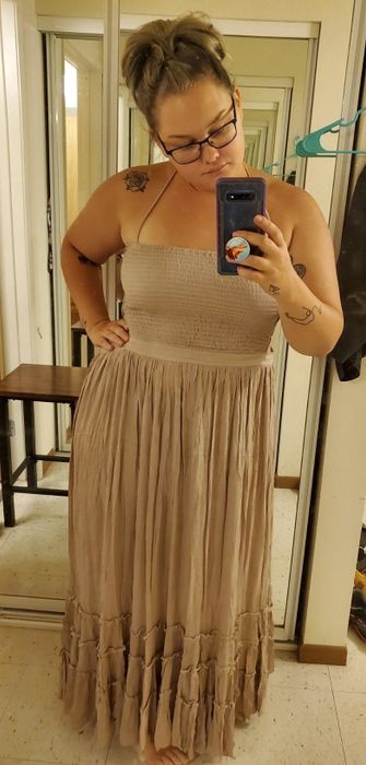 a reviewer capturing a selfie in the tan dress, showcasing its ruched bust and ruffled hem details