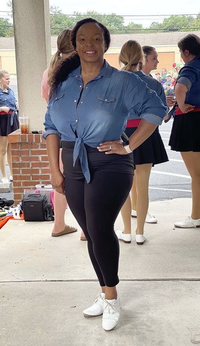 A reviewer wearing a denim tie-waist shirt that ends at the waist