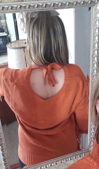 a reviewer photo highlighting a back cutout on an orange sweater