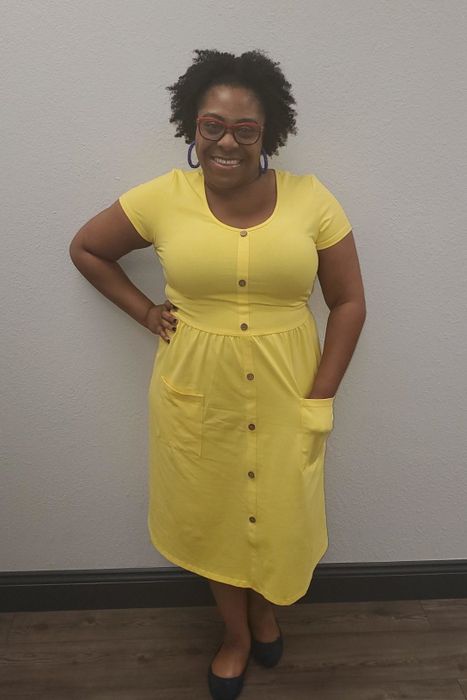 a reviewer wearing the yellow dress, casually placing a hand in one of the side patch pockets