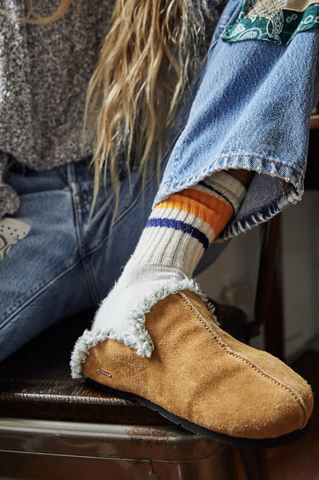 A close-up shot of a model wearing slip-on leather mules with socks