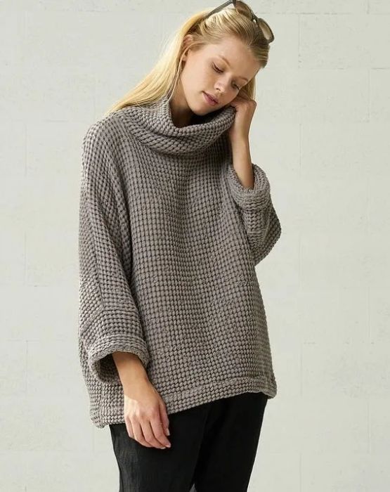 A model showcasing the chunky linen sweater in gray, styled with relaxed black pants