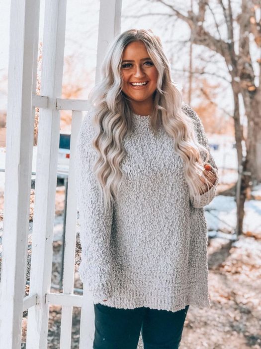 A reviewer wearing an oversized cream-colored sweater