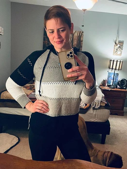 a reviewer modeling the knit hoodie in gray, white, and black