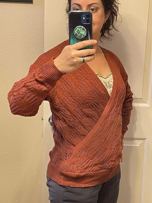 a reviewer showcasing the sweater in a warm rust orange shade