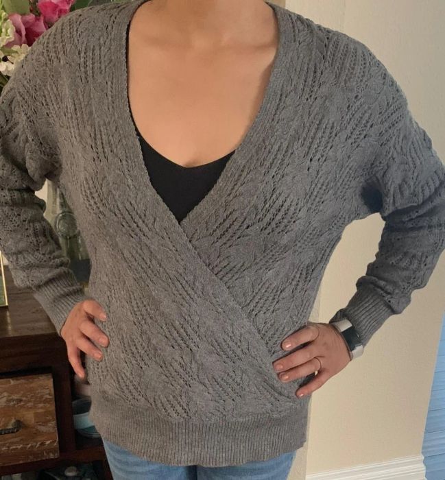 a reviewer wearing the sweater in a soft light gray tone