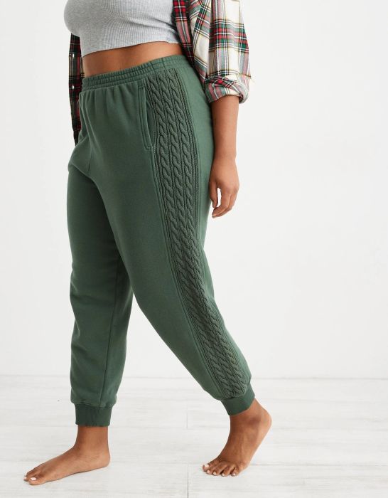 model wearing green joggers with knit panels along the sides of both legs