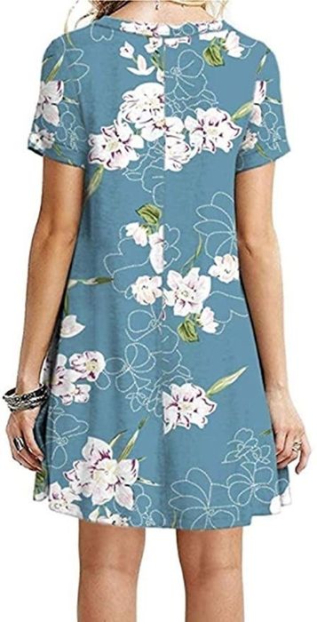 a model displaying the back view of the blue T-shirt dress adorned with a white floral pattern