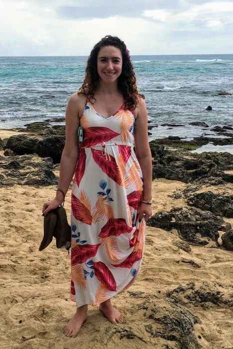 a reviewer wearing the white dress with a pink and orange floral print, captured on a beach