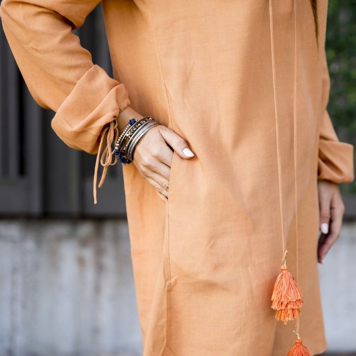 a close-up of the model in the same dress, sliding a hand into one of the side slip pockets