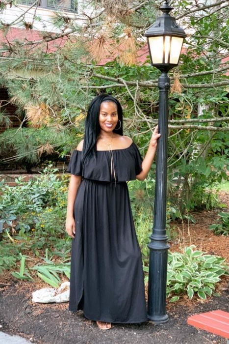 a reviewer modeling the black off-the-shoulder maxi dress