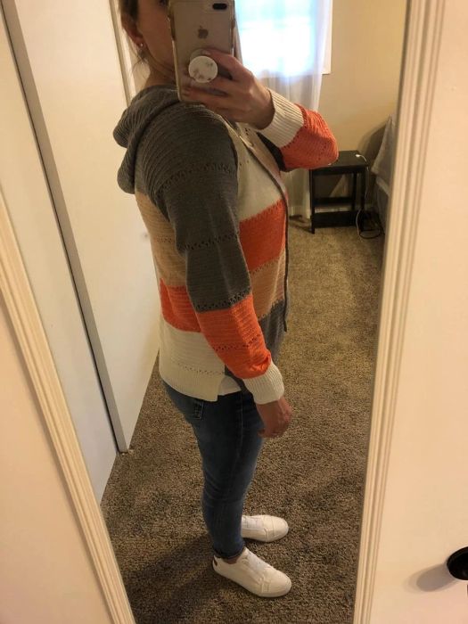 a profile view of the reviewer wearing the knit hoodie with gray, tan, white, and orange stripes