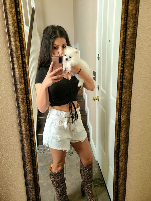 A reviewer in the same crop top in black, styled with high-rise white shorts