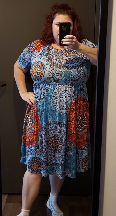 a reviewer wearing the skater dress featuring a blue and orange abstract pattern