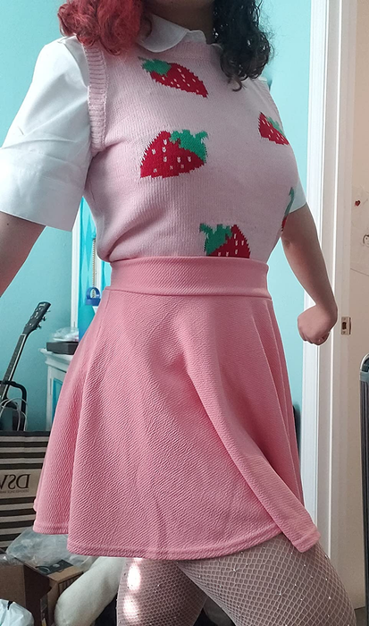 Another reviewer in a strawberry-knit top paired with a pink skirt and white fishnet tights