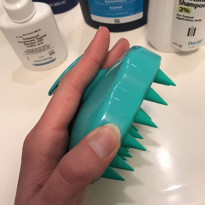 A reviewer holding the blue shampoo brush