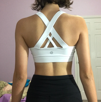 A reviewer turns around to display the interlocking white straps on the back.