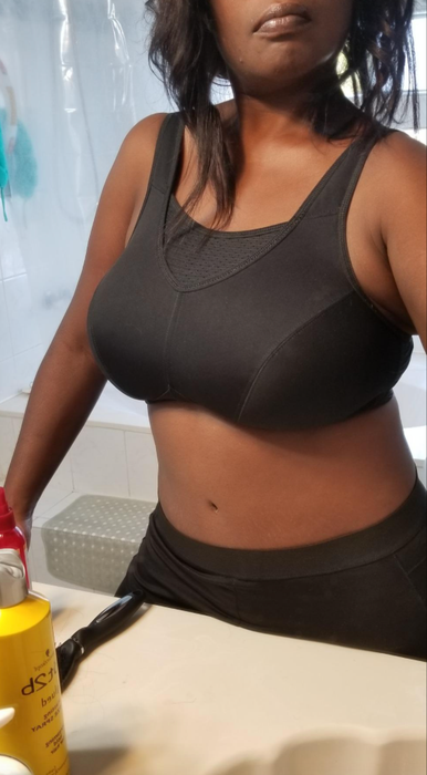 A reviewer is seen wearing the black sports bra with a mesh panel at the top.