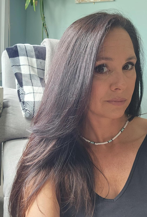 reviewer showcasing a DIY blowout on dark, straight hair