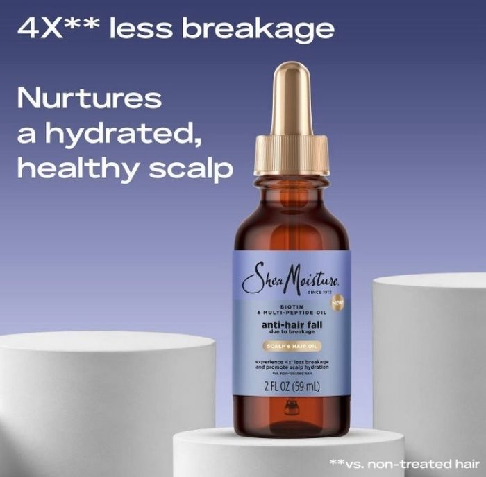 A bottle of Shea Moisture Anti-Hair Fall Multi-Benefit Oil, labeled to reduce breakage and promote a hydrated, healthy scalp, 2 fl oz, displayed on a pedestal