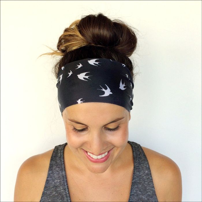 A model is seen wearing a black headband wrap adorned with white bird designs.