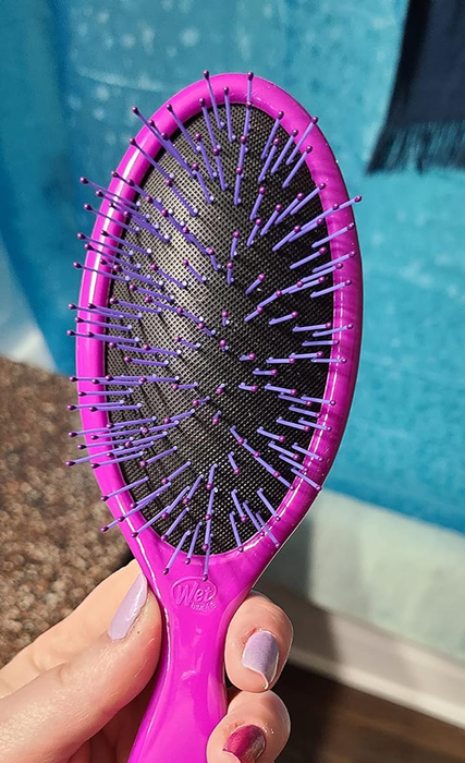 Hand holding a pink Wet Brush with flexible bristles designed for gentle detangling, perfect for haircare tool shopping