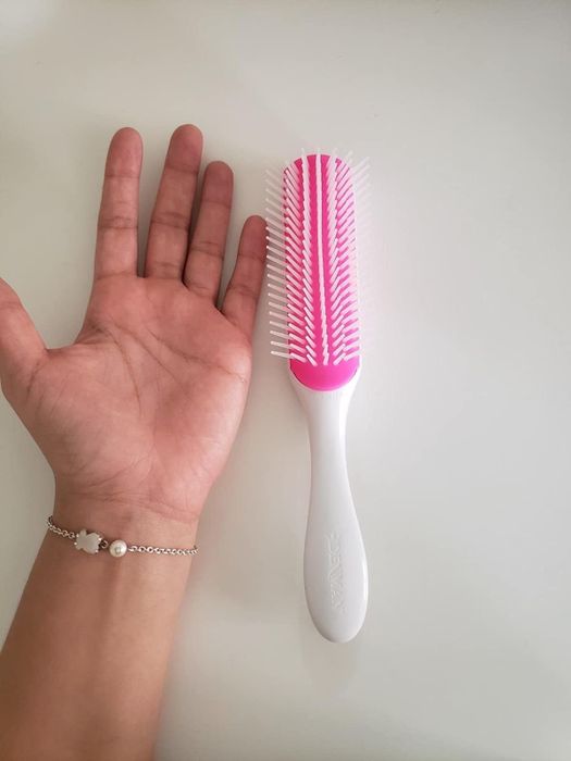 The reviewer's hand is positioned next to a white brush placed on a table.