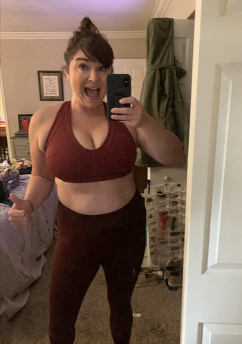 A reviewer showcases the front view of a red v-neck sports bra.