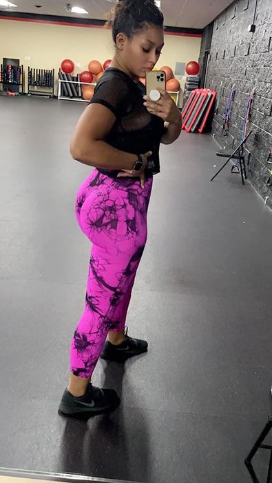 A reviewer showcasing black and pink leggings paired with a black top and shoes