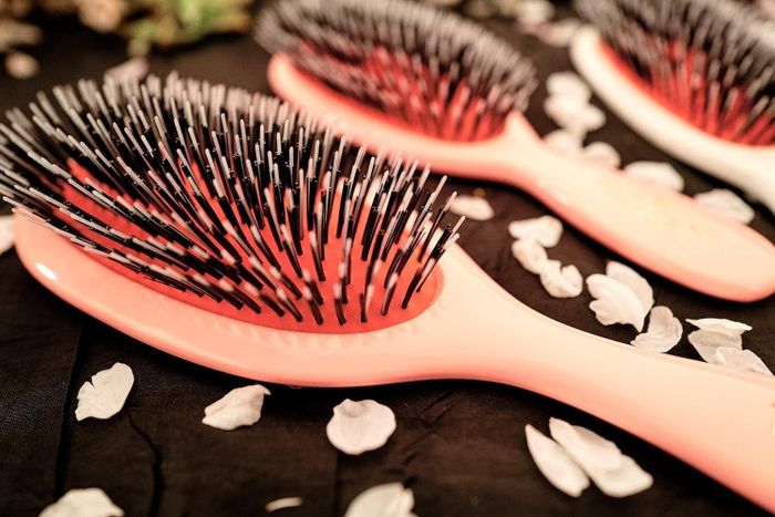 Hairbrushes with bristles neatly displayed on a surface adorned with scattered petals.