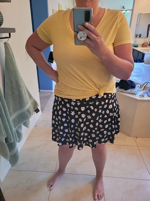 A reviewer showcasing a yellow top paired with a blue skort featuring yellow and white daisies