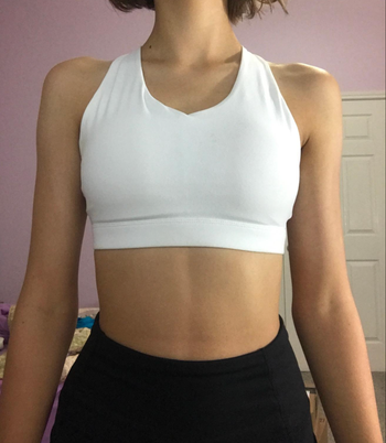 A reviewer wearing a white scoop neck sports bra.