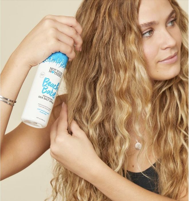 A person applying wave spray to their hair