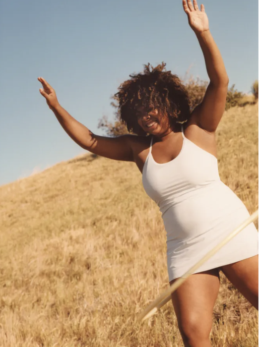 A model is seen wearing a white strappy dress that ends mid-thigh.