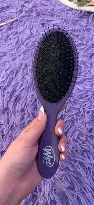 A reviewer holding a purple Wet Brush.