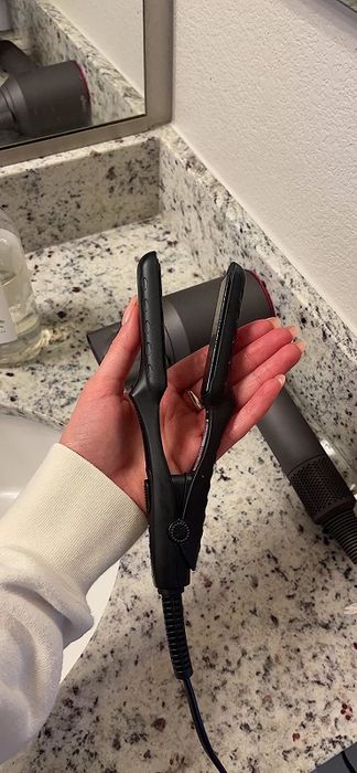 A reviewer holding the mini flat iron in the palm of their hand