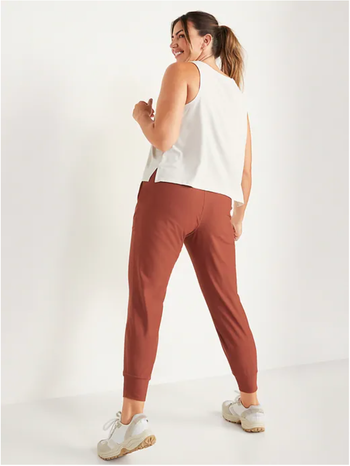 A model is seen wearing a pair of burnt orange joggers.