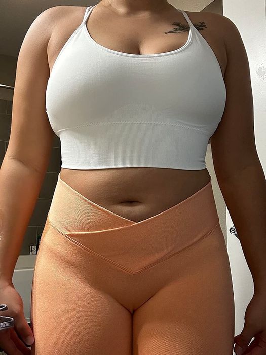 a reviewer modeling a white sports bra paired with orange bottoms