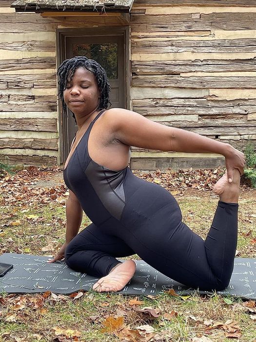 reviewer showcasing the black unitard in a yoga pose