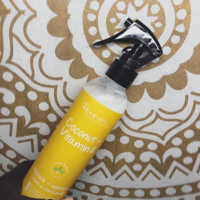 A bottle of Renpure Coconut & Vitamin E leave-in conditioner with a spray nozzle, positioned against a patterned background