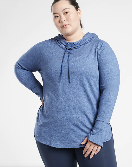 A model is seen wearing a blue hoodie with thumbholes.