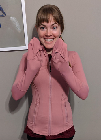 A reviewer is seen wearing a pink hoodie, using the sleeves as makeshift mittens.