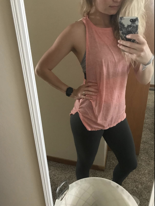 A reviewer is seen wearing a pink tank that reaches mid-hip and has a crewneck design.