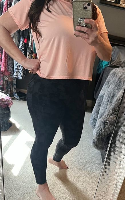 A reviewer wearing an orange tee paired with grey pants